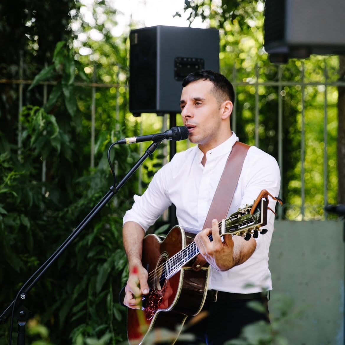 Phil Giner en tenue élégante, chantant avec sa guitare lors d’un événement